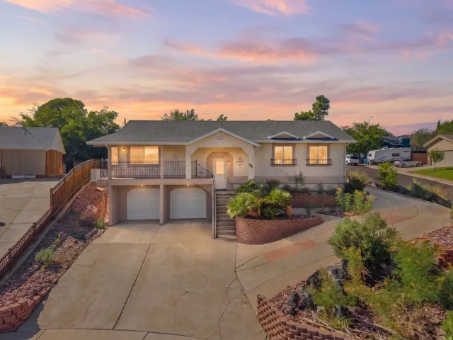 Split-level home featuring an elevated front balcony, dual garage doors, and a curved concrete driveway
