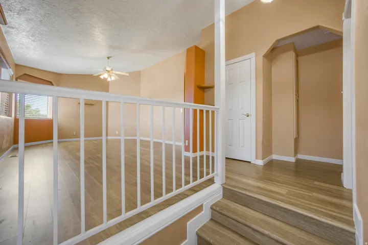 Wood-finish flooring throughout, with a white painted railing and balusters