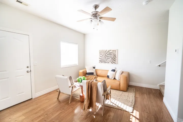 Wood-finish flooring, white walls, ceiling fan with light, white trim, and a window for natural light