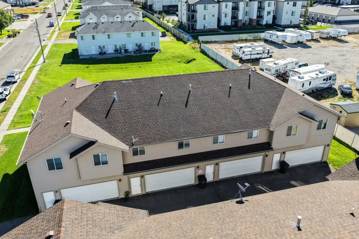 Multi-unit property featuring a brown shingle roof, beige exterior siding, multiple garage doors, and front entry doors