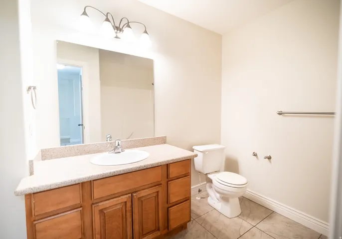 Vanity with wood cabinetry, speckled countertop, and integrated sink