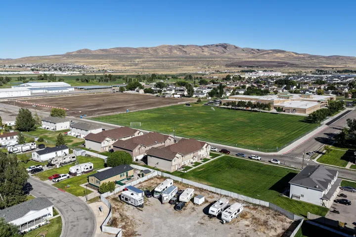 Expansive mountain scenery, suburban neighborhood, large green field, residential structures, paved roads