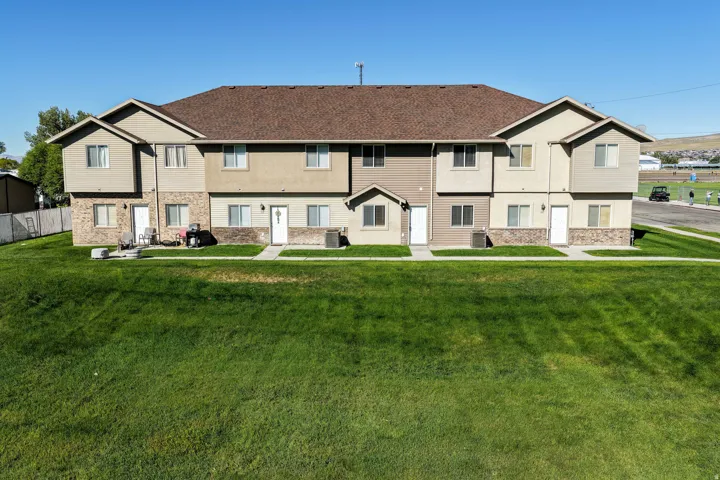 Multi-unit structure with tan siding, brown shingle roof, and stone facade accents