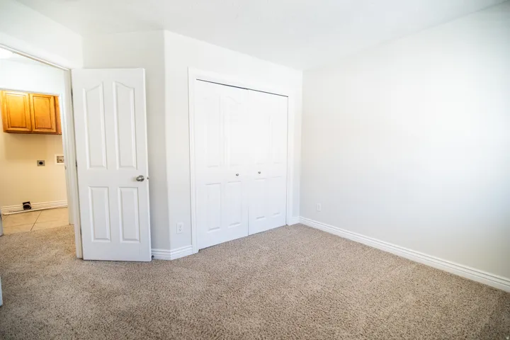 Light-colored carpeting, white walls, and bifold closet doors