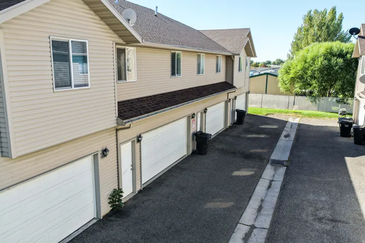 Tan siding exterior with multiple garage bays and asphalt pavement