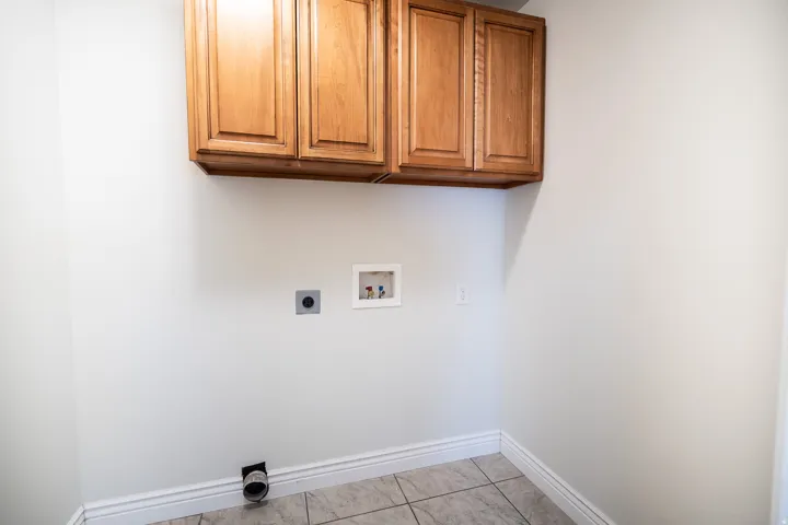Built-in wood cabinetry, light-toned wall paint, tile flooring, and essential utility hookups