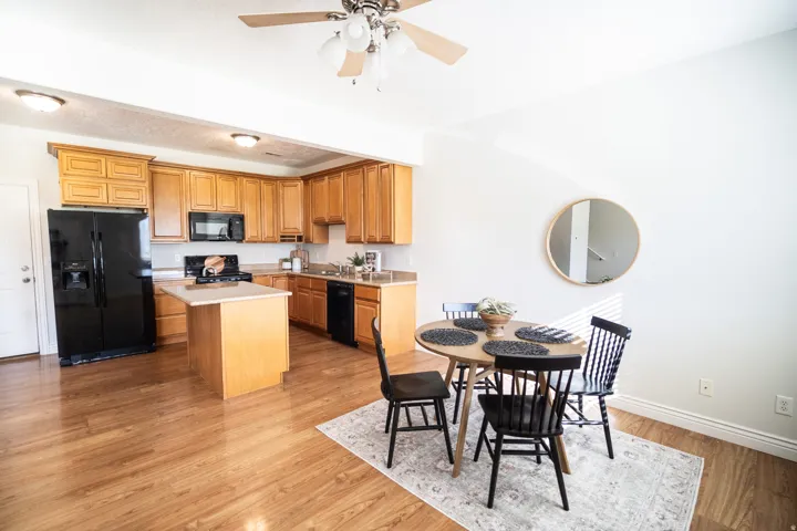Kitchen featuring wood-finish flooring, wood cabinetry, a center island, and black appliances