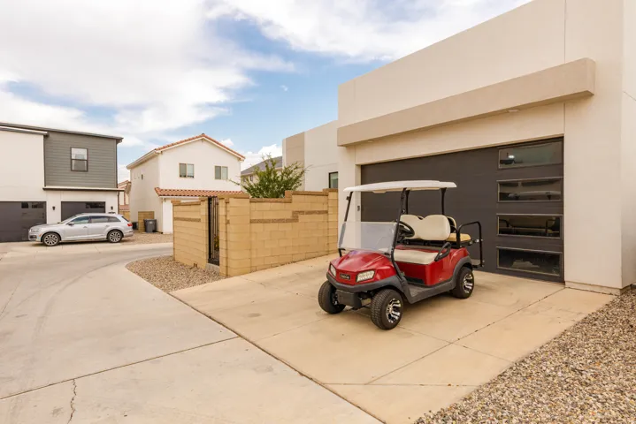 Modern driveway featuring a wide concrete apron with decorative gravel borders, direct access to a dark-finish garage with horizontal panel detailing, and ample space for vehicles and recreational equipment