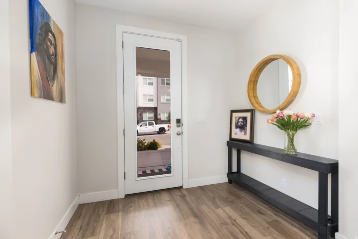 Entryway featuring a full-light panel door, wood-finish flooring, and a console table with an open shelf