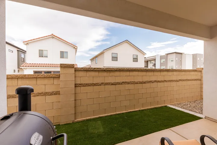 Covered patio with concrete flooring, artificial turf, gravel landscaping, and a block wall perimeter