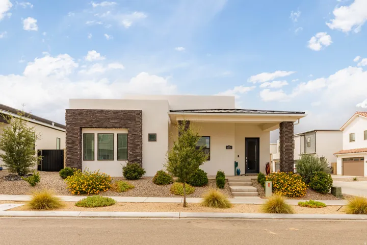Modern architectural design featuring a clean-lined cream and brick exterior with expansive glazing, complemented by low-maintenance desert landscaping with ornamental grasses and strategic plantings