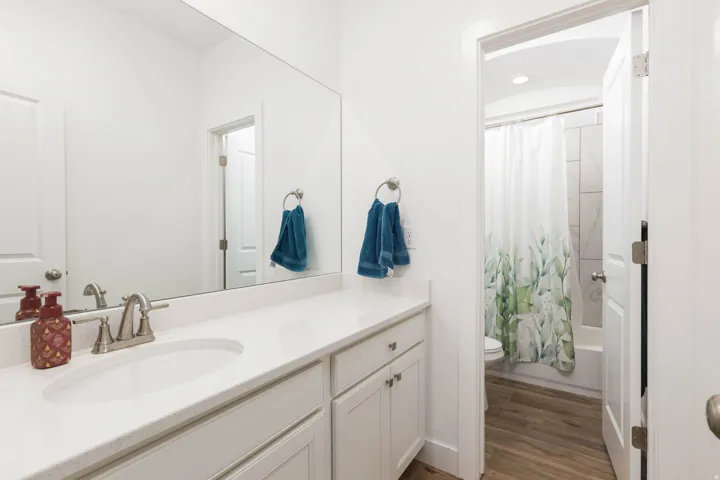 Spa-inspired primary bathroom featuring a dual-sink vanity with white cabinetry, quartz countertop, and brushed nickel fixtures