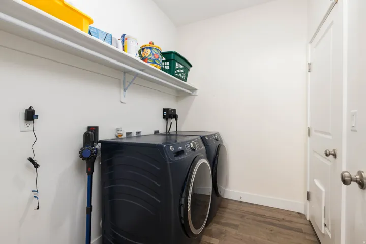 Laundry space with wood-finish flooring and a white wall-mounted shelf