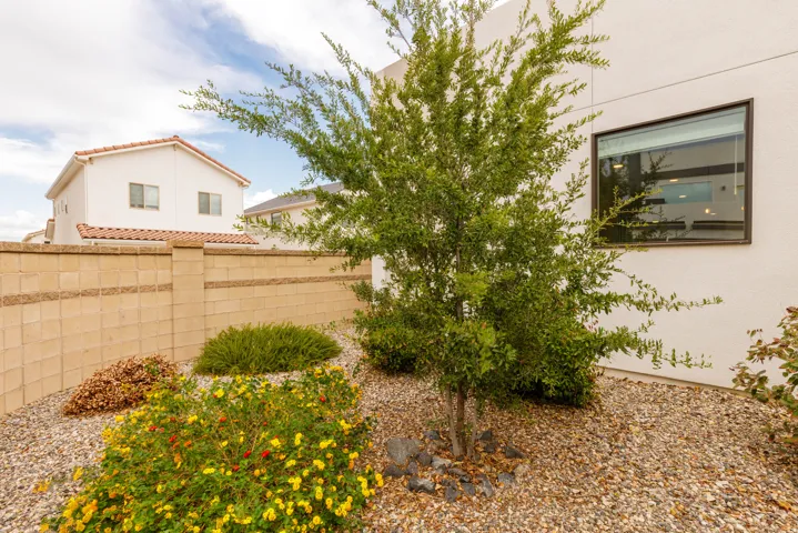 Landscaped exterior featuring a decorative block wall, mature shrubs, and a large window