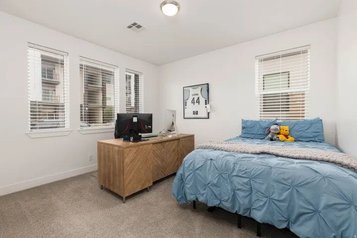 Neutral wall color, carpeted flooring, three windows with blinds, and recessed lighting
