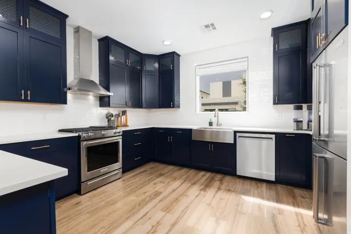 Kitchen featuring dark blue cabinetry, white countertops, stainless steel appliances, white subway tile backsplash, and wood-finish flooring