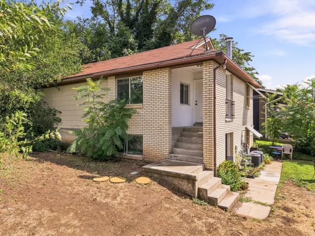 Brick exterior with white trim, concrete steps, and a red-toned shingle roof