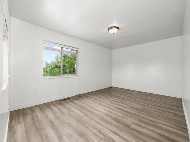 Wood-finish flooring, white painted walls, and a single window with blinds