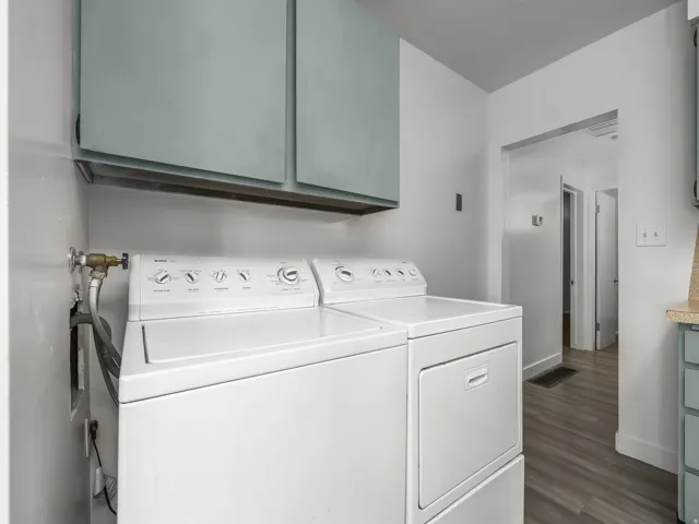 Laundry area featuring overhead cabinetry, wall-mounted water hookups, and wood-finish flooring