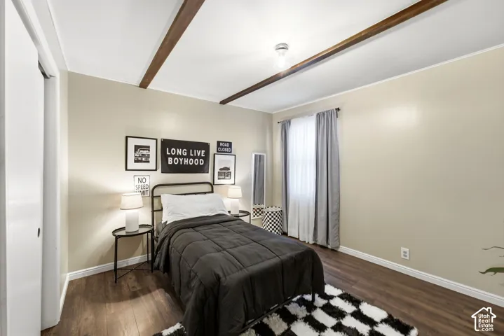 Vaulted ceiling with exposed wood beams, wood-finish flooring, and light-colored walls