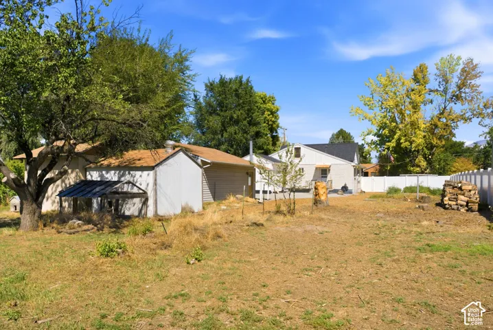 Expansive backyard featuring a white privacy fence, mature trees, and a detached shed