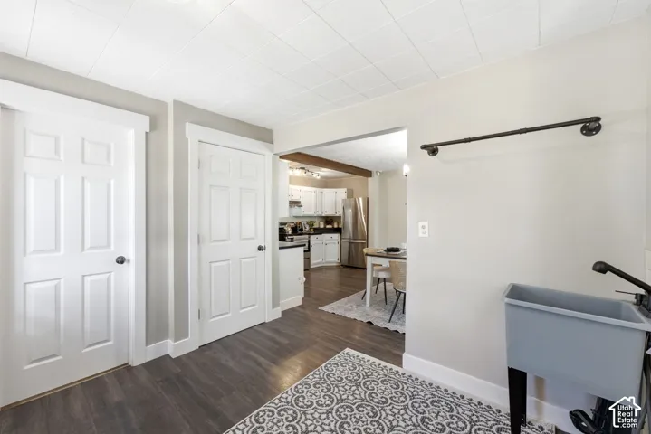 Wood-finish flooring, paneled interior doors, and a utility sink with a black faucet