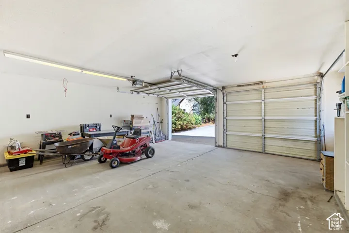 Attached two-car garage with concrete flooring, fluorescent lighting, and an automatic garage door opener