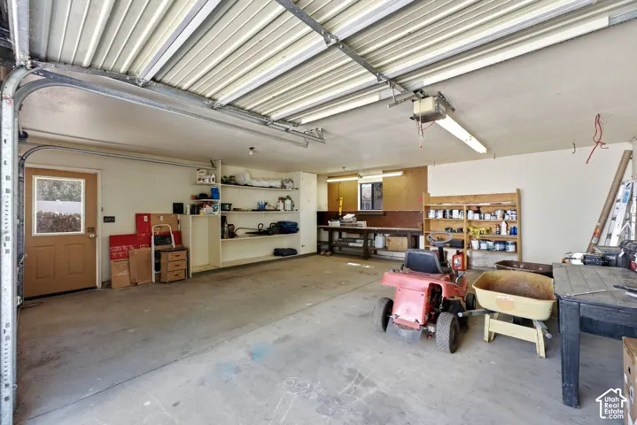 Spacious garage with concrete flooring, built-in shelving, and a dedicated workbench area
