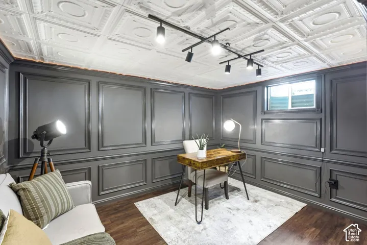 Bedroom/Office in basement Decorative tin ceiling, dark panel molding, wood-finish flooring, recessed window, and track lighting fixture