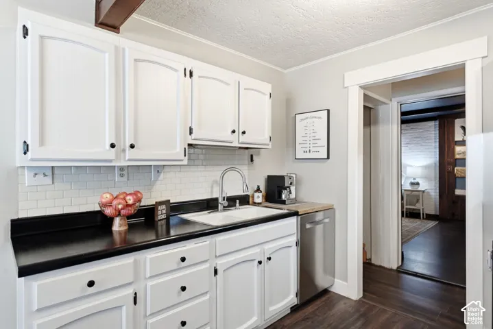 White cabinetry with black hardware, black countertops, white subway tile backsplash, stainless steel dishwasher, and wood-finish flooring