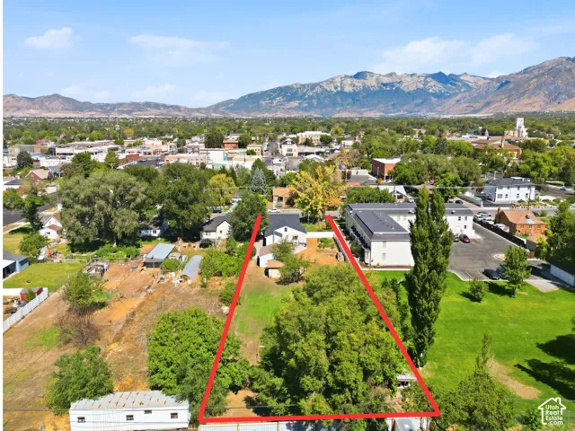 Expansive lot with mature trees, a clear grassy area, and distant mountain scenery