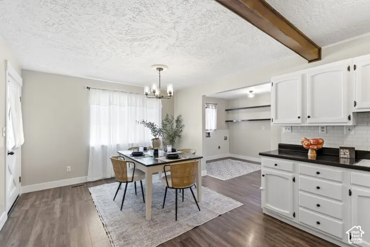 Wood-finish flooring throughout, white cabinetry with dark hardware, dark countertops, and a white subway tile backsplash
