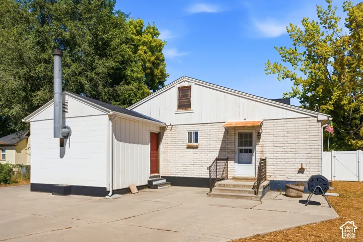 Exterior featuring white brick siding and a concrete patio