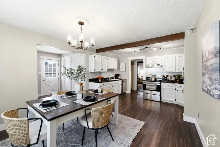 Open-concept dining and kitchen space featuring wood-finish flooring, white cabinetry, dark countertops, and stainless steel appliances