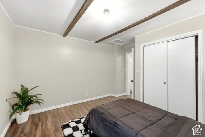 Wood-finish flooring, light gray wall color, white ceiling, white trim, and a white sliding closet door