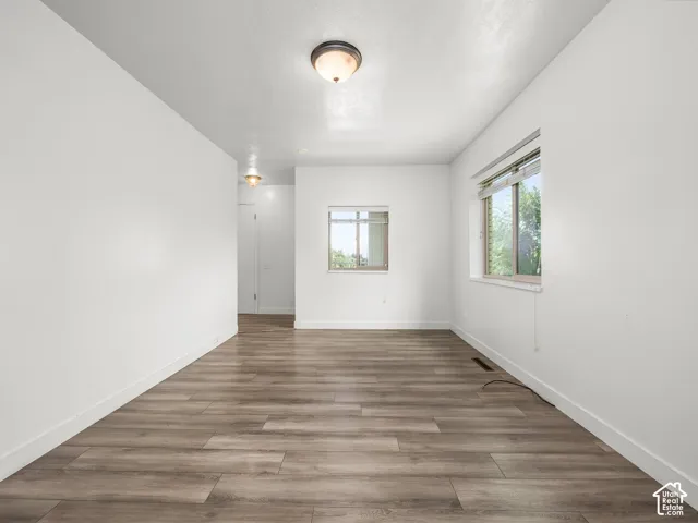 Wood-finish flooring, white walls, and two windows with blinds
