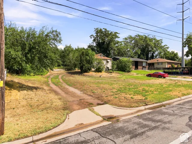 Spacious lot with mature trees and established landscaping, concrete driveway, and single-story residence set back from the street