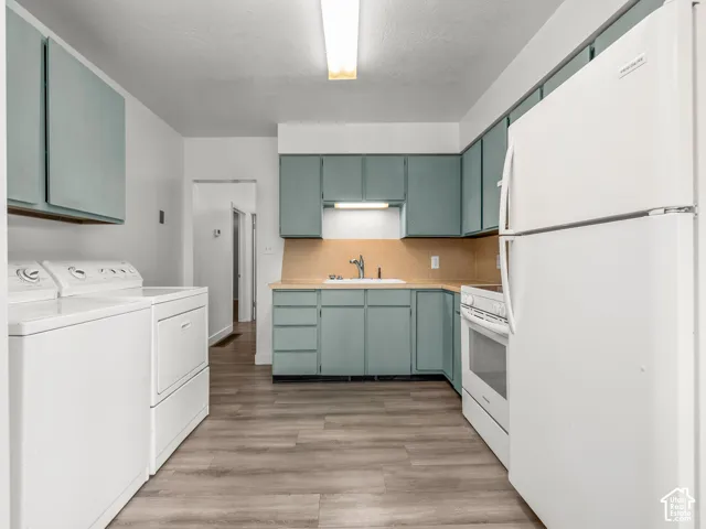 Kitchen featuring wood-finish flooring, teal cabinetry, and white appliances