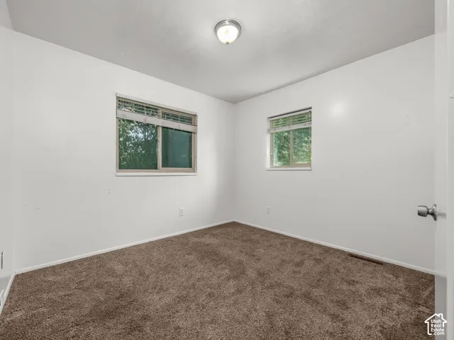 Recessed windows with blinds, wall-mounted ceiling light fixture, and brown carpet flooring