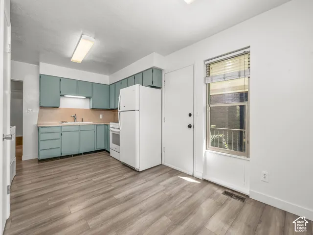 Kitchen featuring wood-finish flooring, a white refrigerator, a white range, and a window with blinds