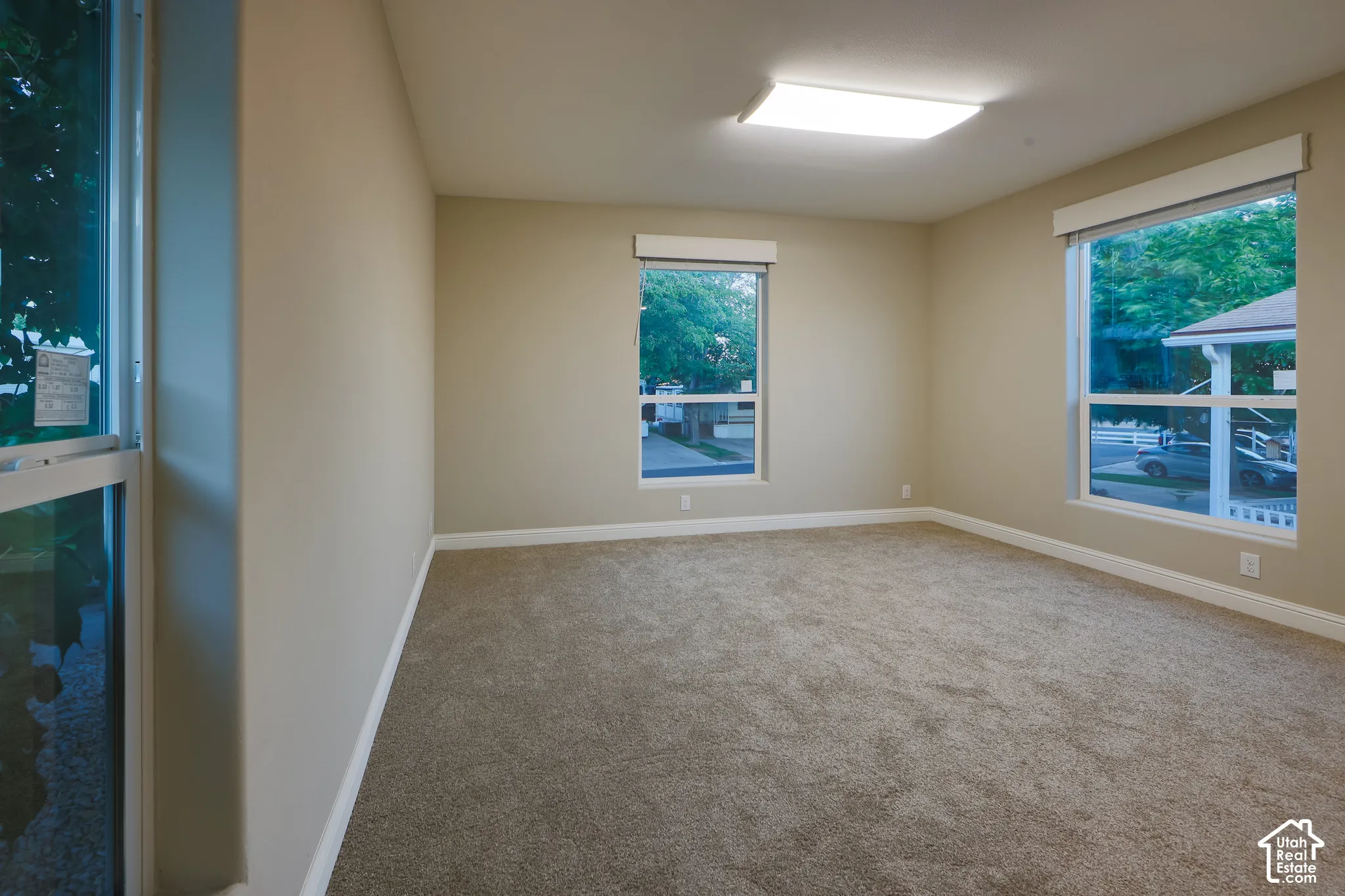 Neutral-toned walls, carpeted flooring, multiple windows with blinds, and recessed lighting
