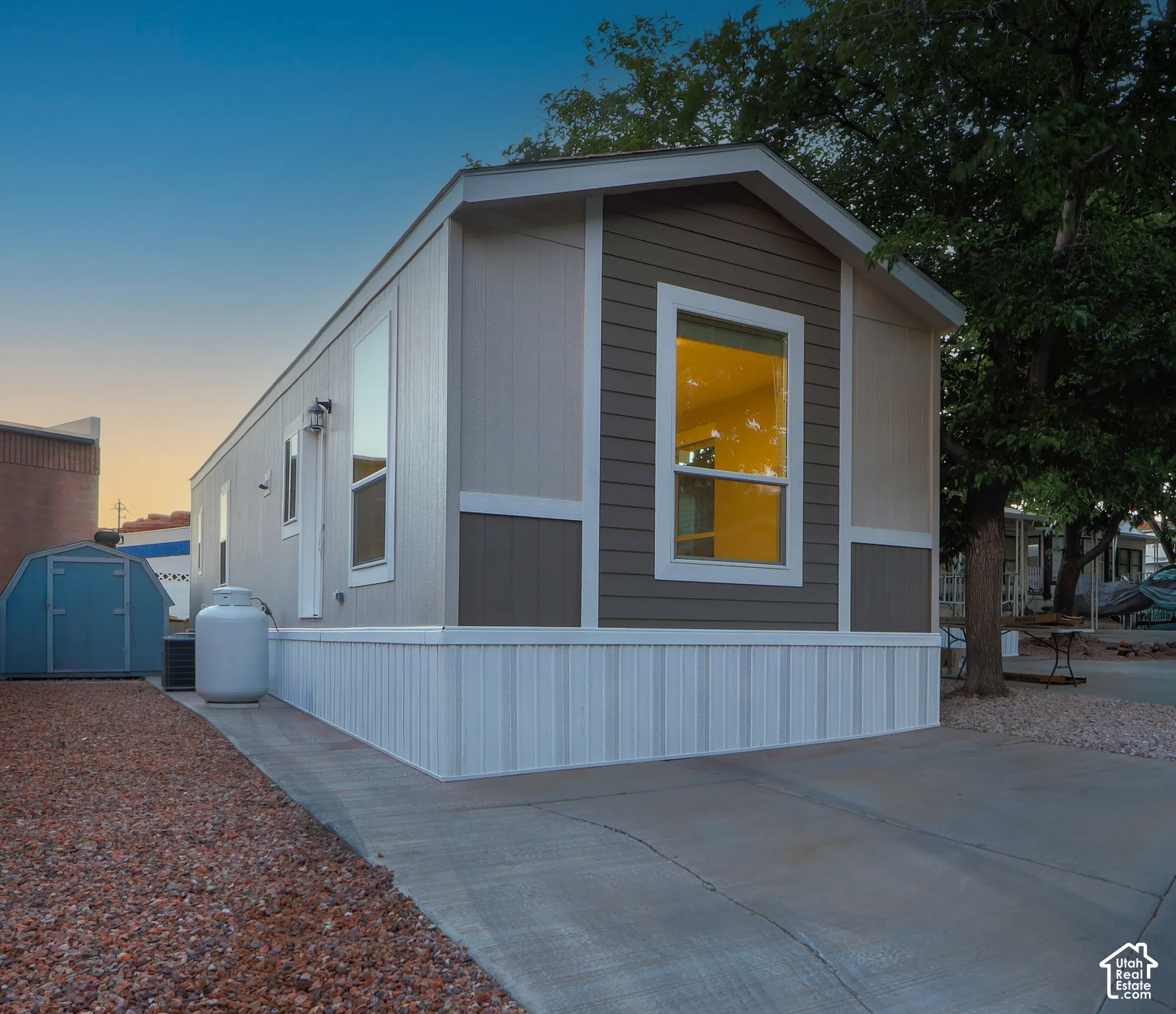 Exterior siding with contrasting colors, white trim accents, prominent front window, concrete driveway, and a gravel-covered side yard
