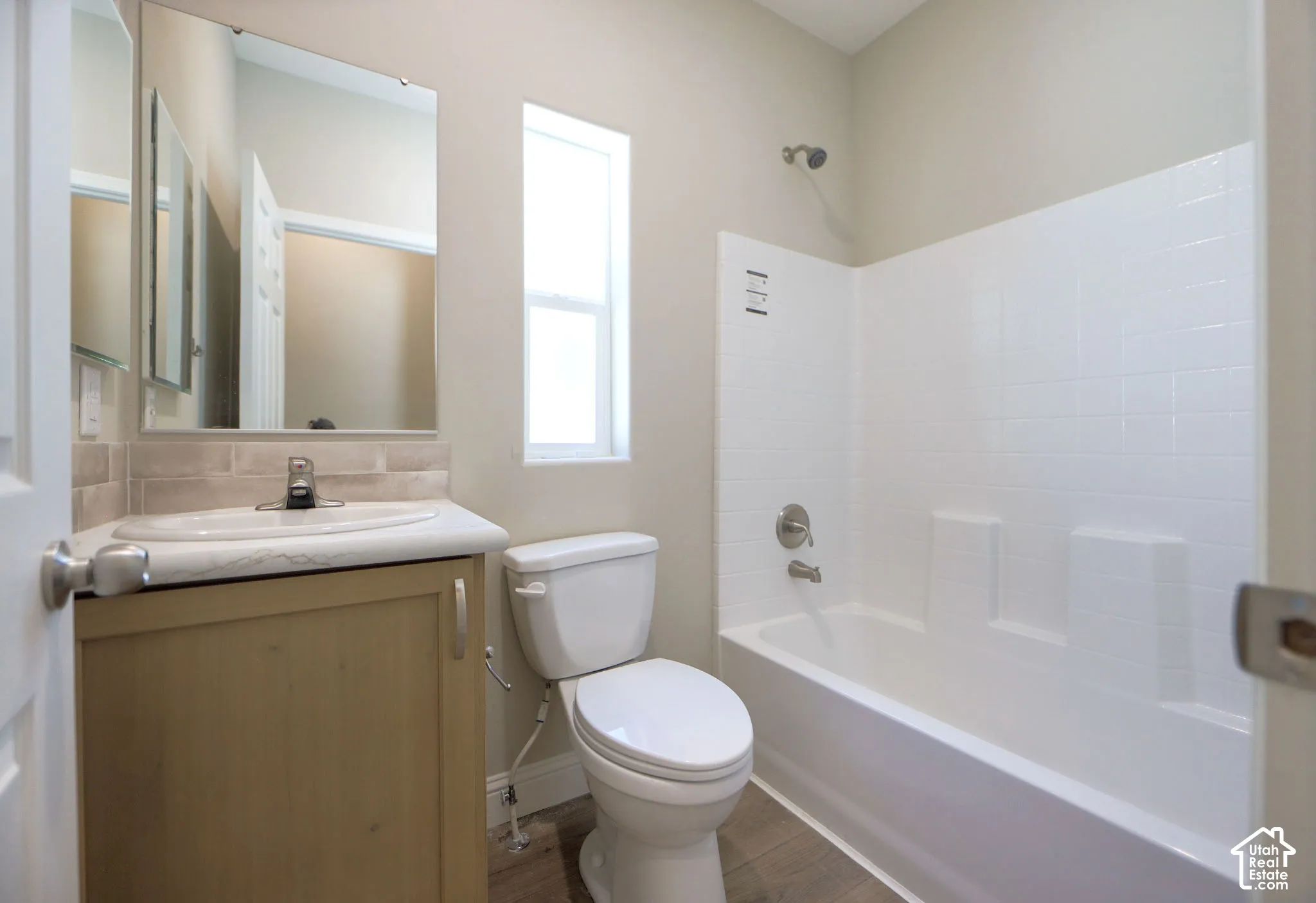 Wood-finish flooring with a white bathtub and shower surround