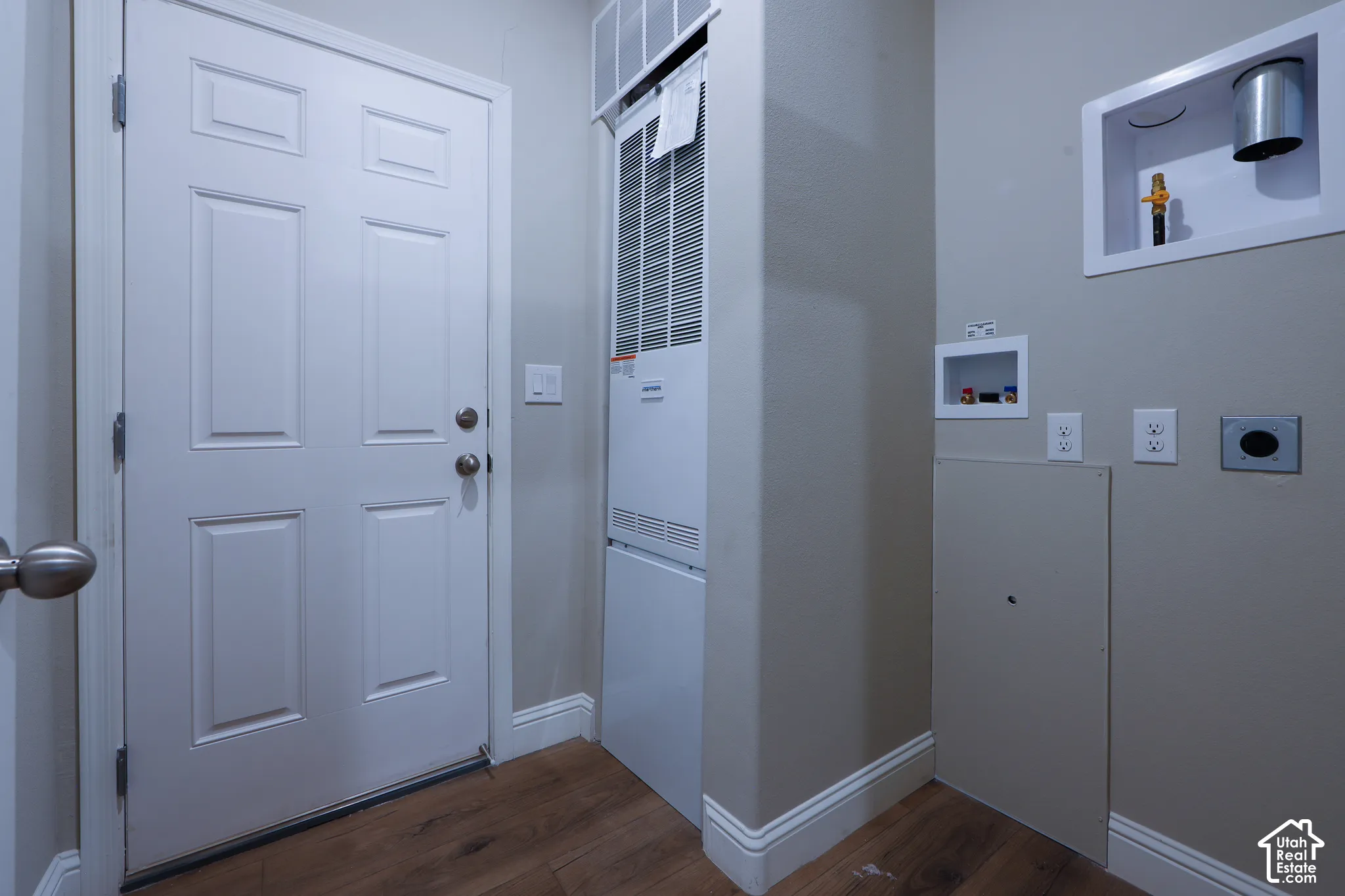 White paneled door with brushed nickel hardware, wood-finish flooring, and light gray wall paint