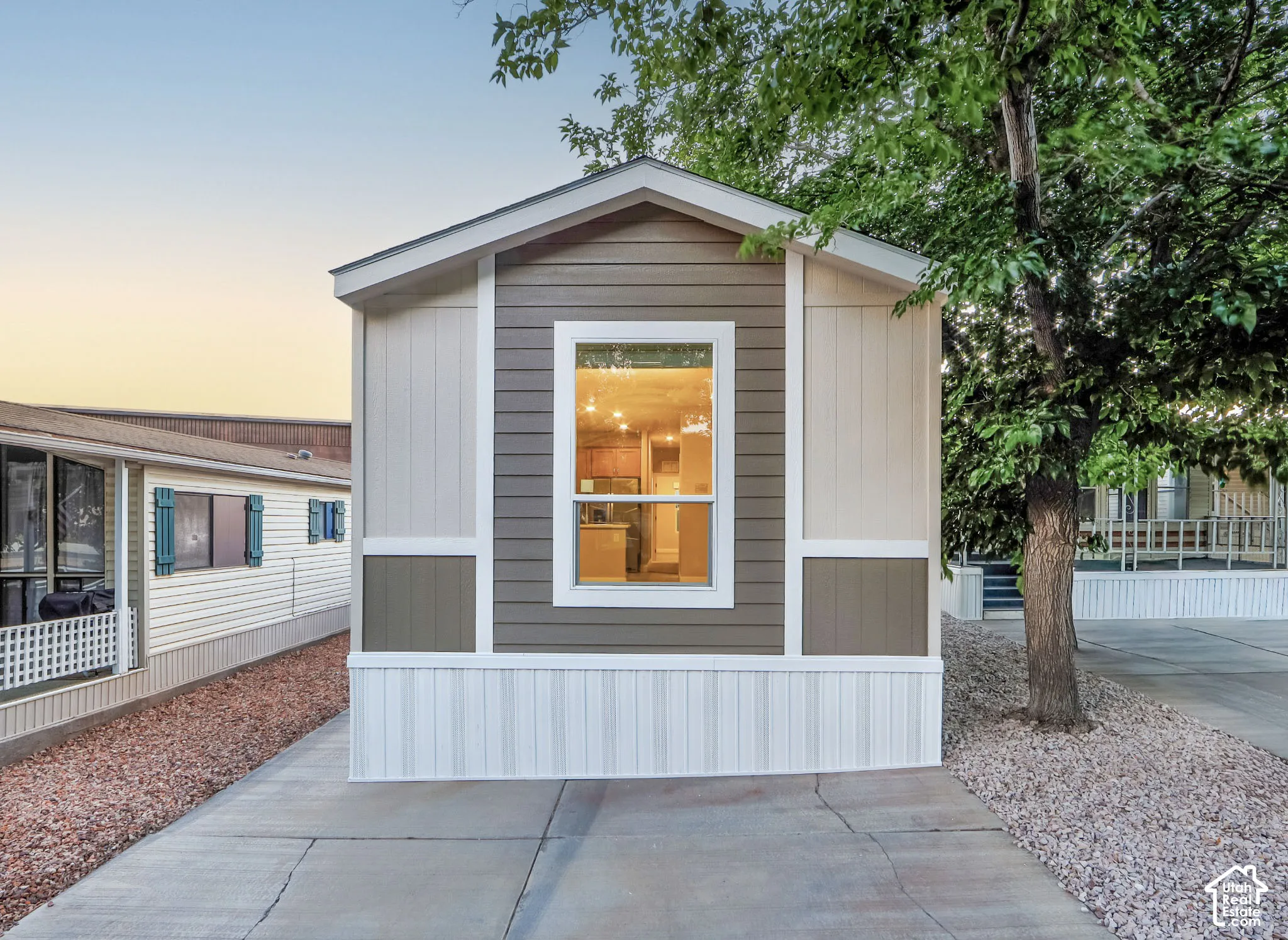 Contemporary exterior siding in a multi-tone finish with white trim, a single-pane window, and a paved concrete driveway