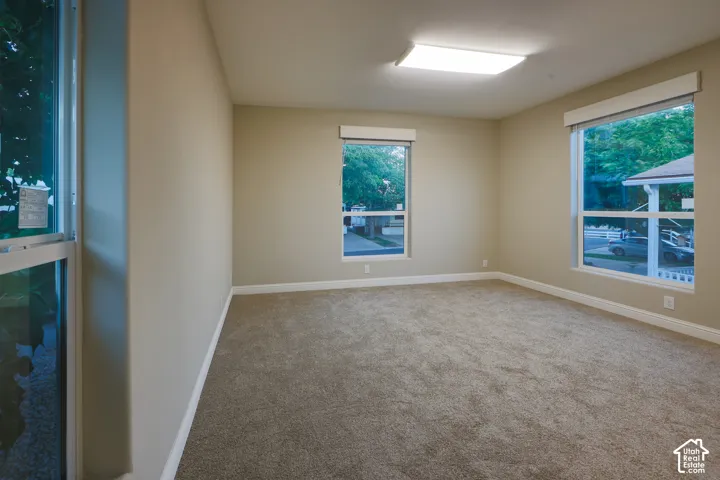 Neutral-toned walls, carpeted flooring, multiple windows with blinds, and recessed lighting