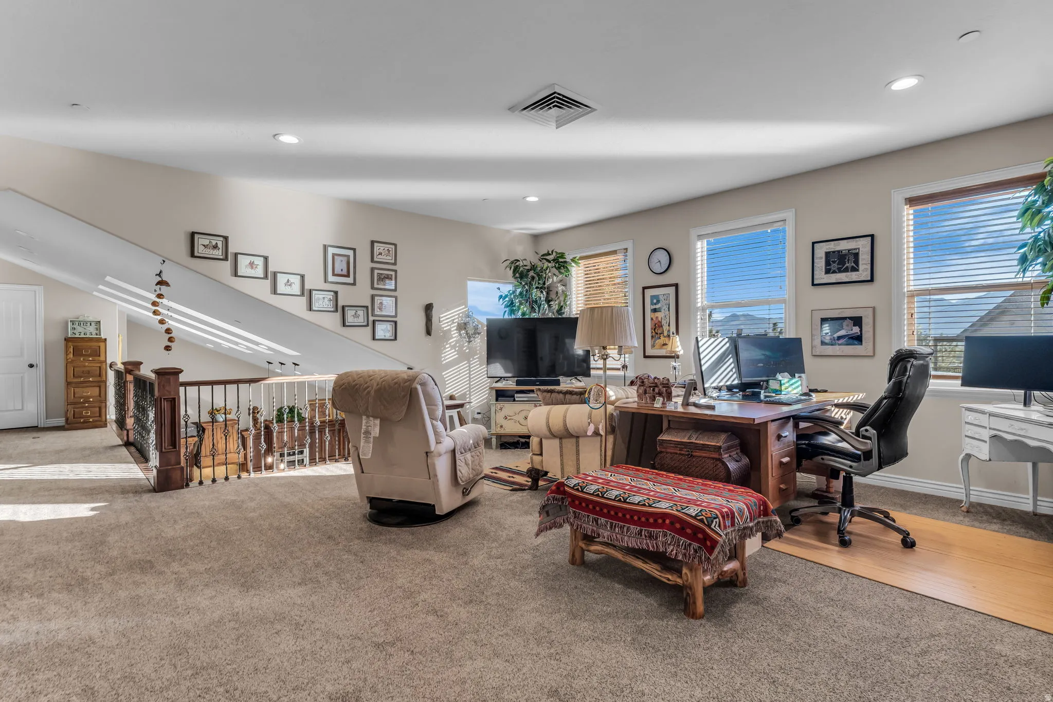 Carpeted open loft area with multiple windows providing natural light