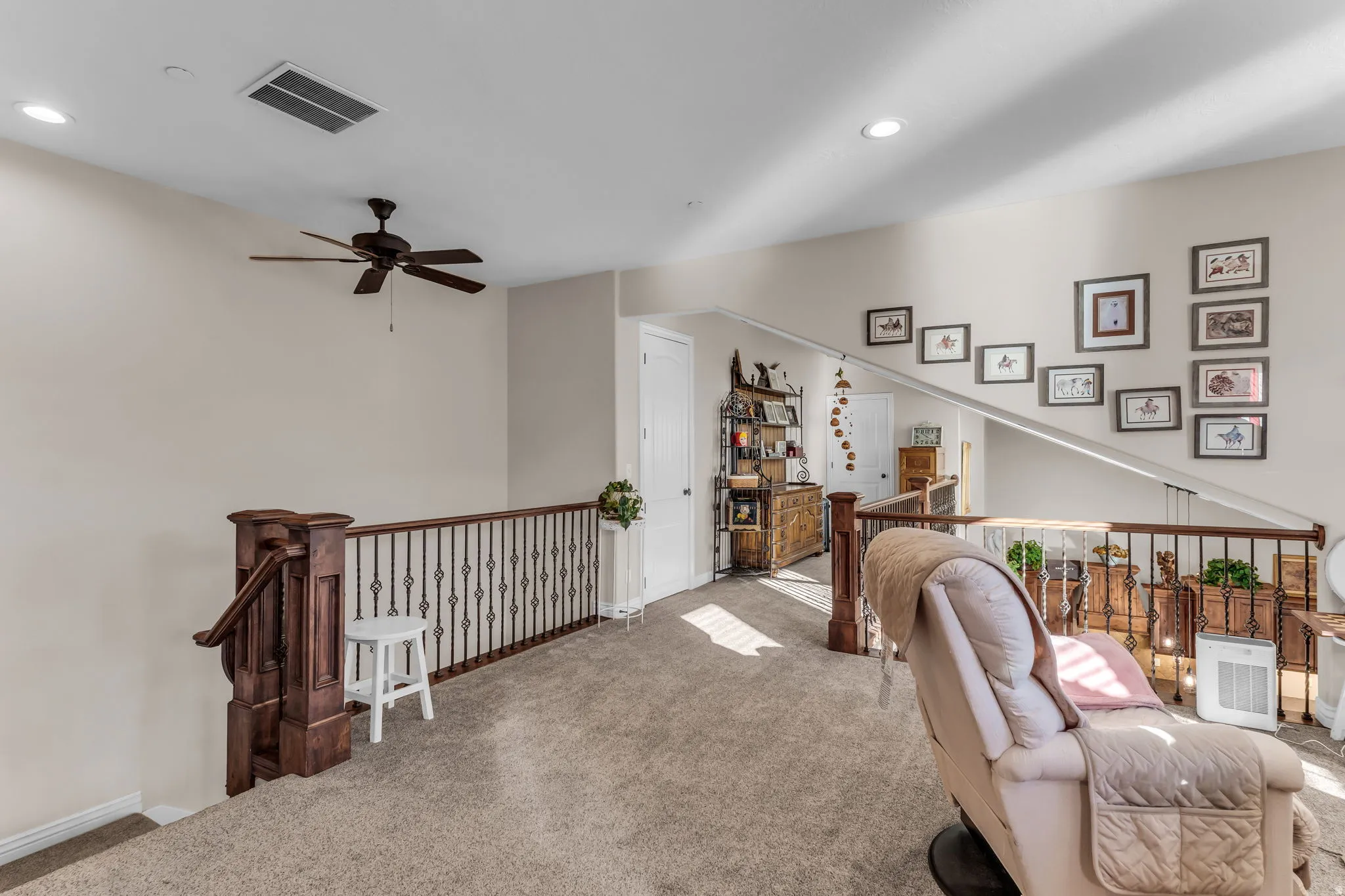 Carpeted loft space featuring recessed lighting, a ceiling fan, and wrought iron railings