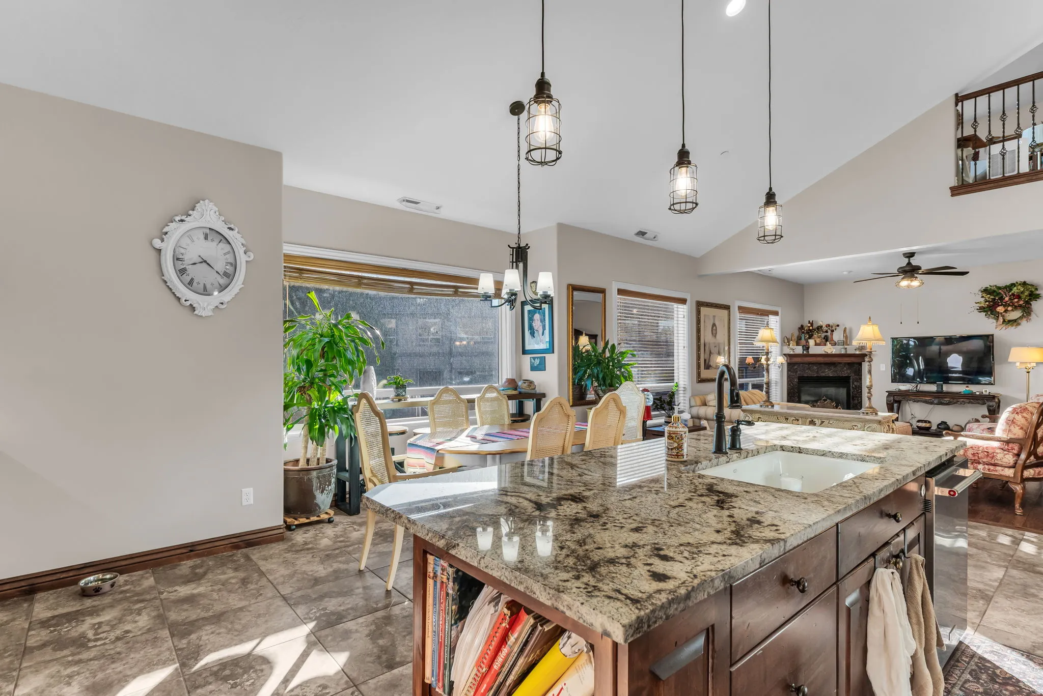 Kitchen island with granite countertops, undermount sink, and dark wood cabinetry