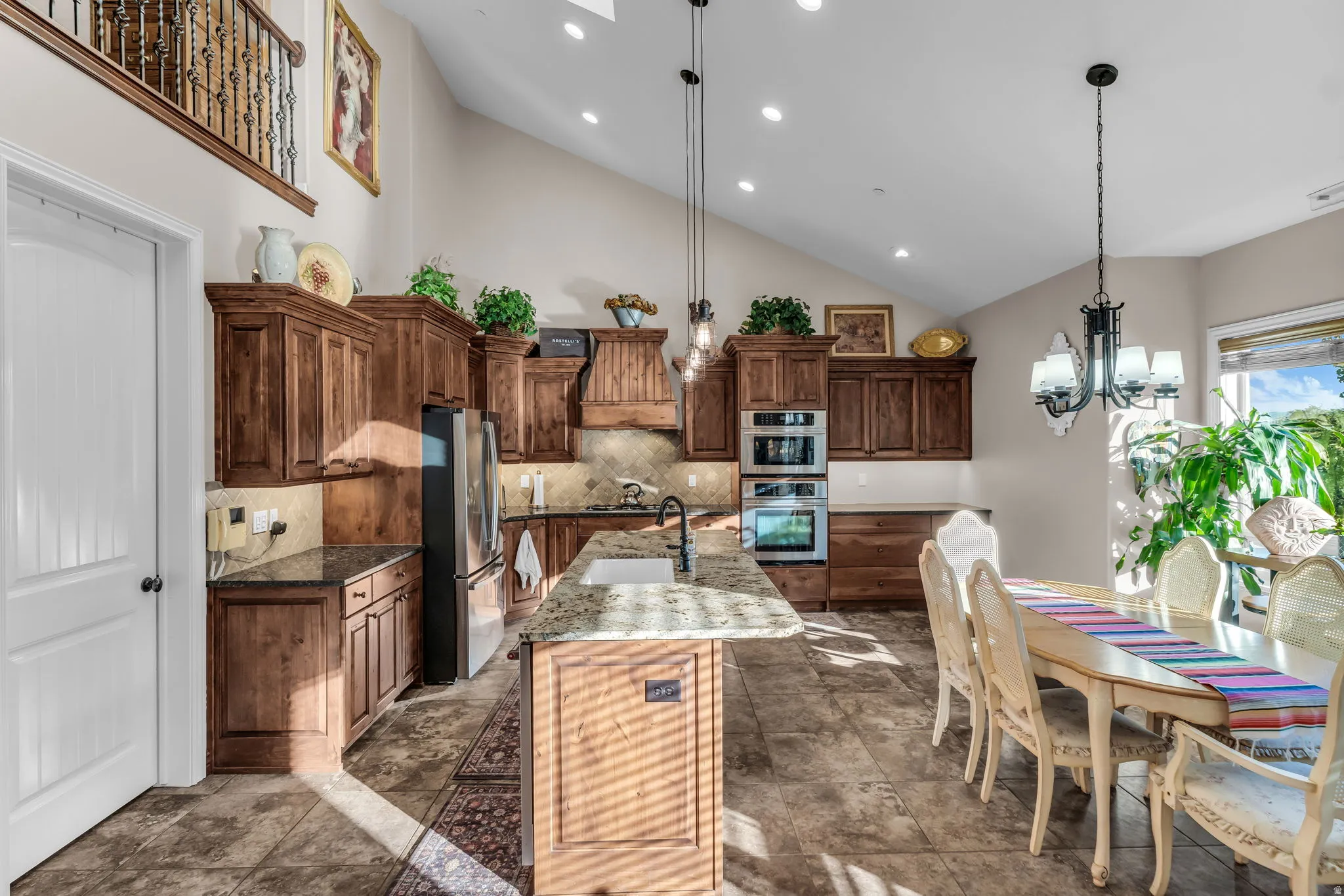 Open-concept kitchen and dining area featuring vaulted ceilings, recessed lighting, and tile flooring